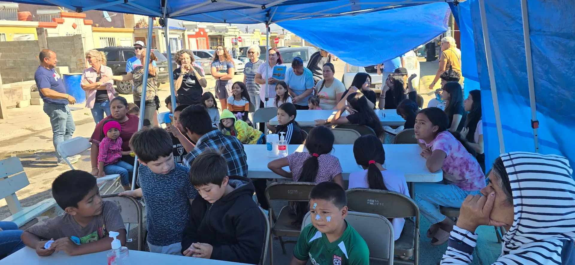 Food for the hungry: children and families sharing a meal at an outdoor community feeding in Ensenada