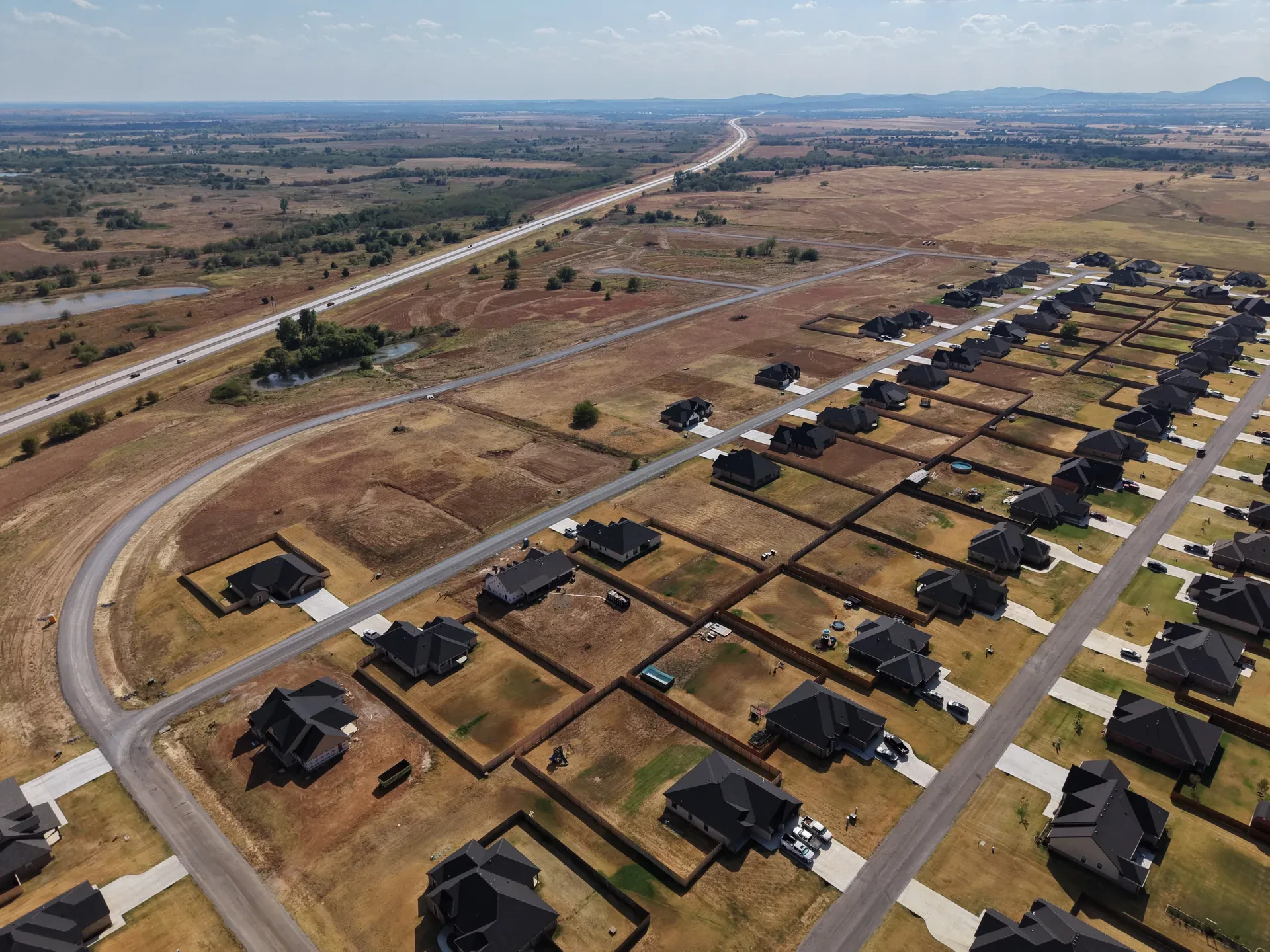 Subdivision aerial view of Legacy Creek Estates with homes, fences, and empty lots in the developing neighborhood