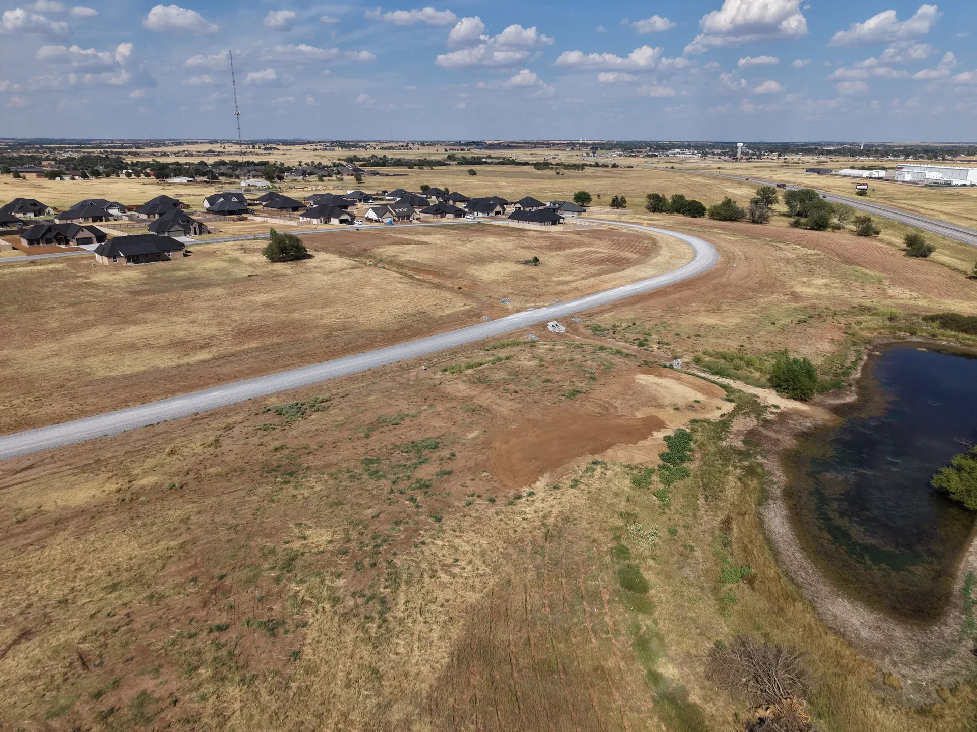Rural landscape around Legacy Creek Estates with open grass fields and new construction homes in the distance