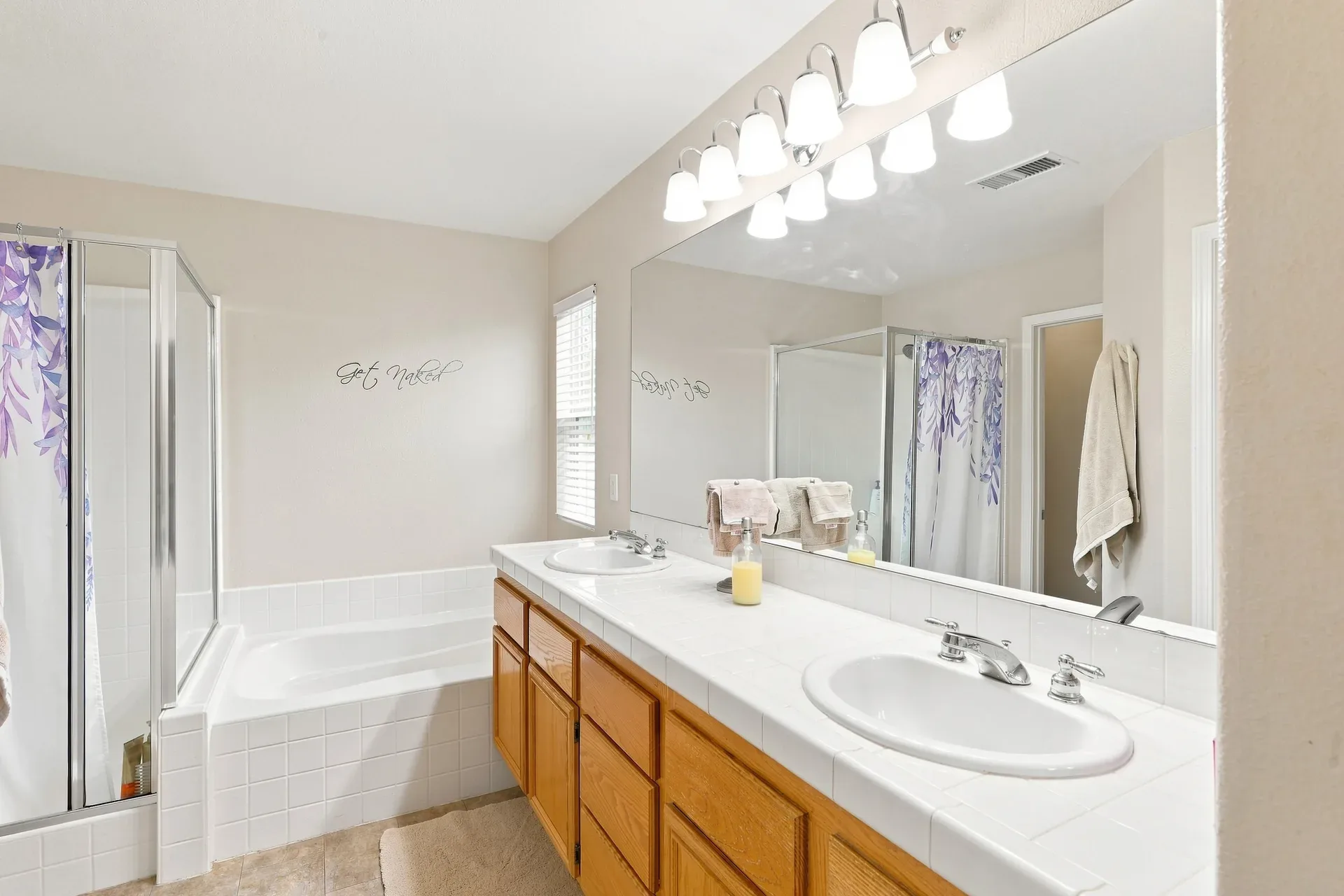 Primary bathroom with oak vanity and white tile