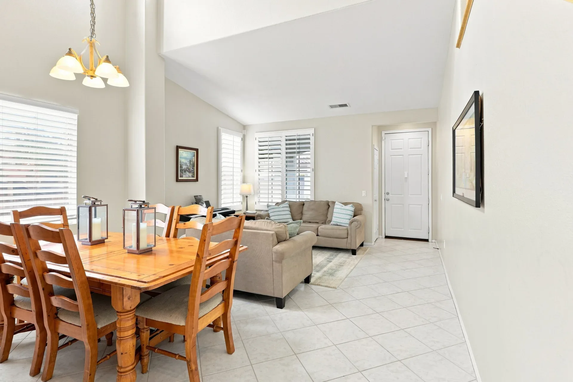 Open-concept living and dining area with vaulted ceilings and tile floors