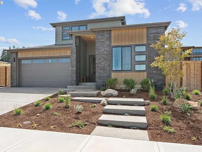 The facade: Charcoal brick, warm timber siding, and a landscaped approach