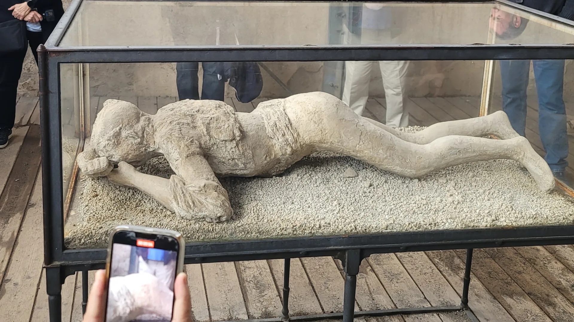 Plaster casts of Pompeii victims displayed behind glass