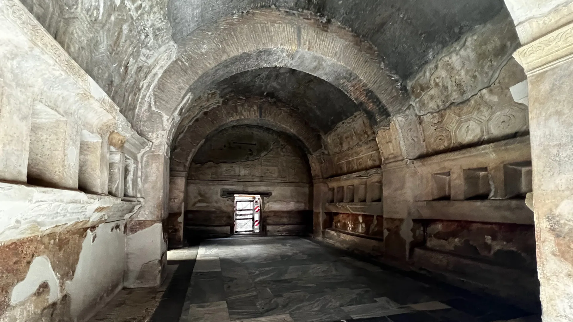 A barrel-vaulted stone chamber among the ruins of Pompeii
