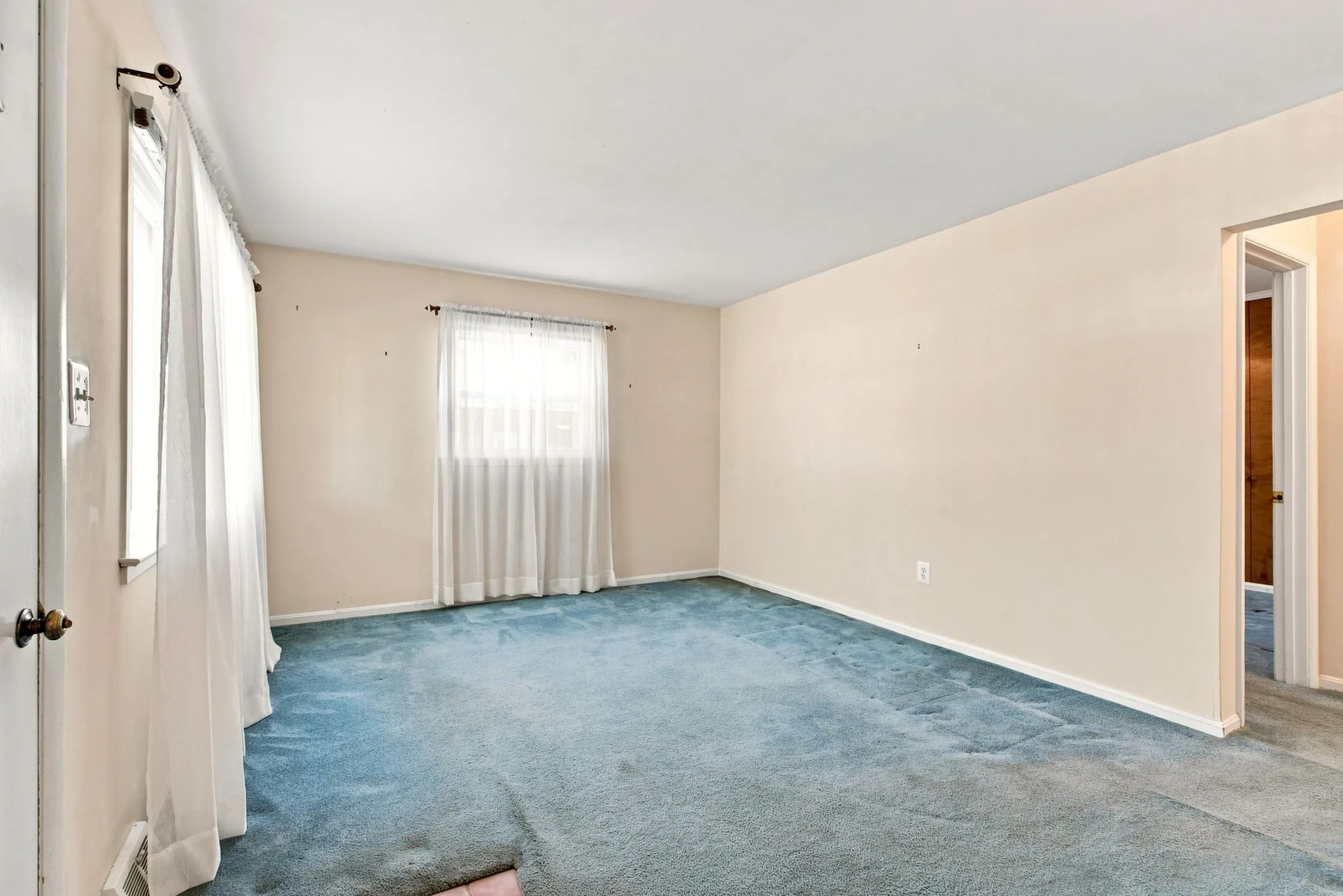 Bedroom with blue wall-to-wall carpeting and two bright windows