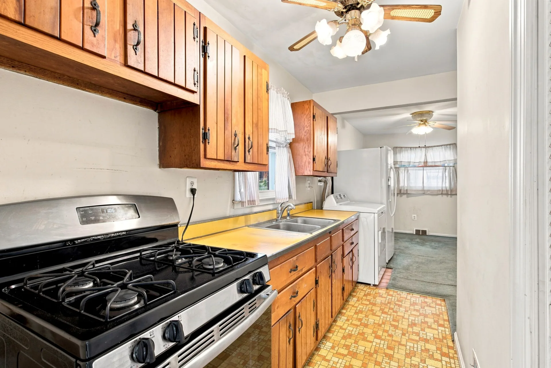 Galley kitchen with honey-toned wood cabinets and mosaic tile floor