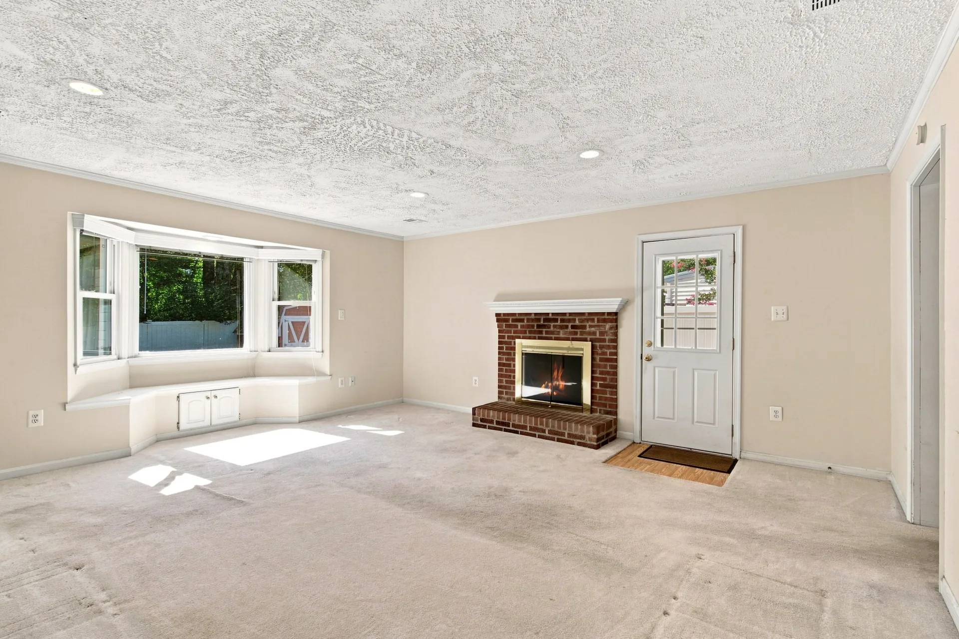 Living room with a red brick wood-burning fireplace and a built-in window seat in 179 Colburn Drive