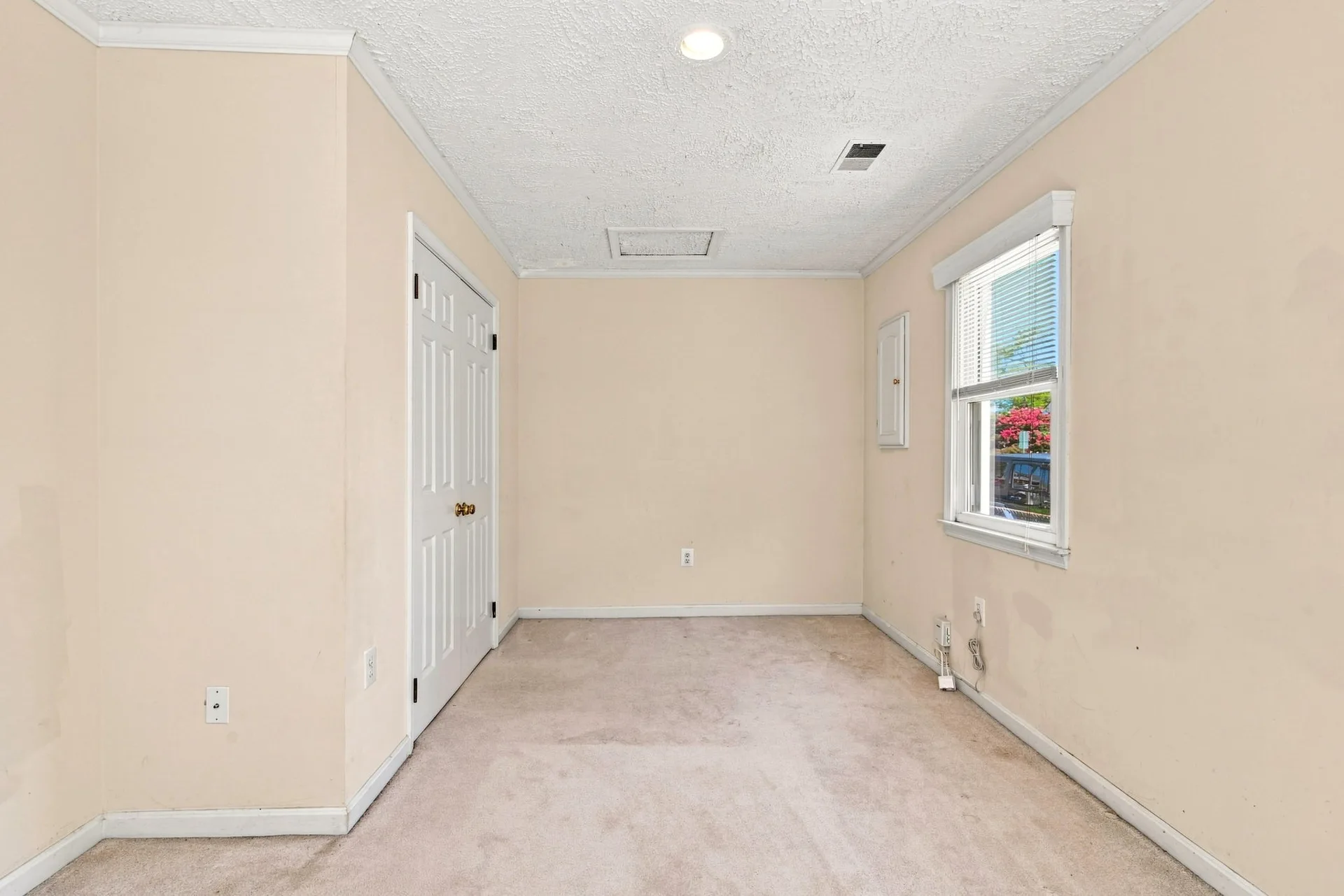 Vacant bedroom with neutral walls and beige carpet