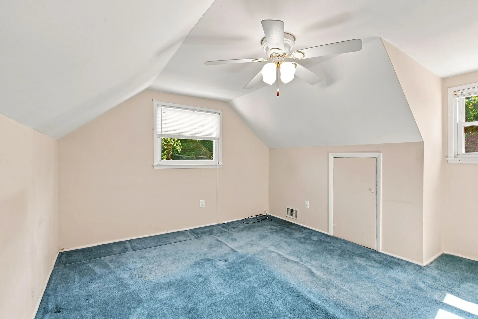 Upper bedroom with sloped ceiling detail and blue carpet