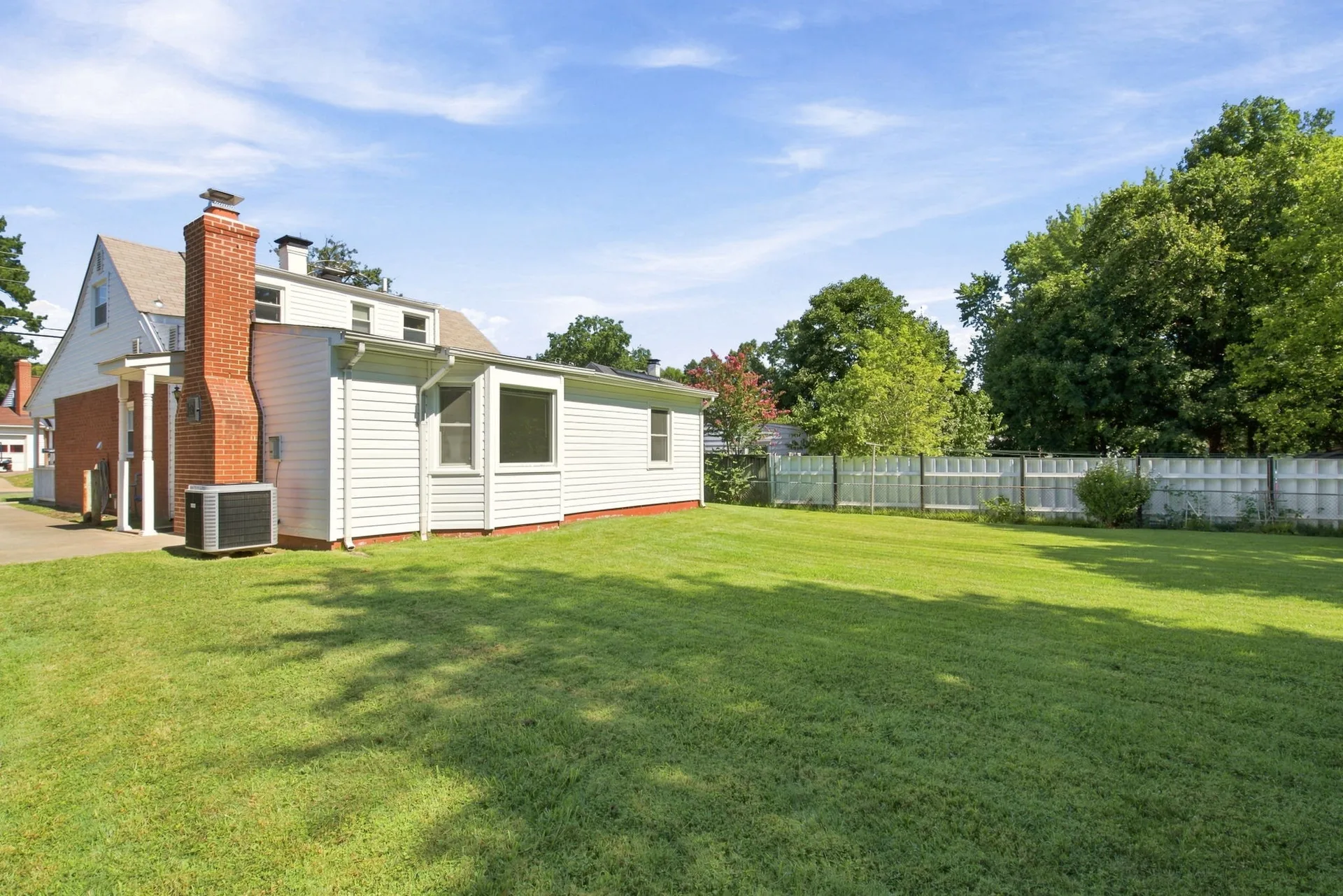 Backyard view toward the house with white siding and red brick chimney