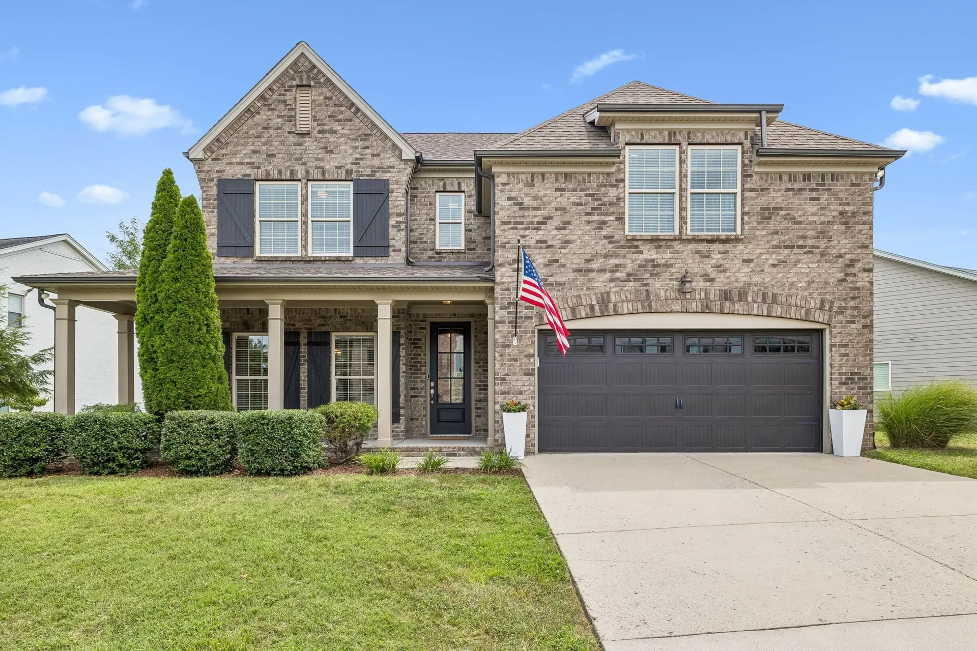 Traditional two-story brick home with dark shutters in daylight