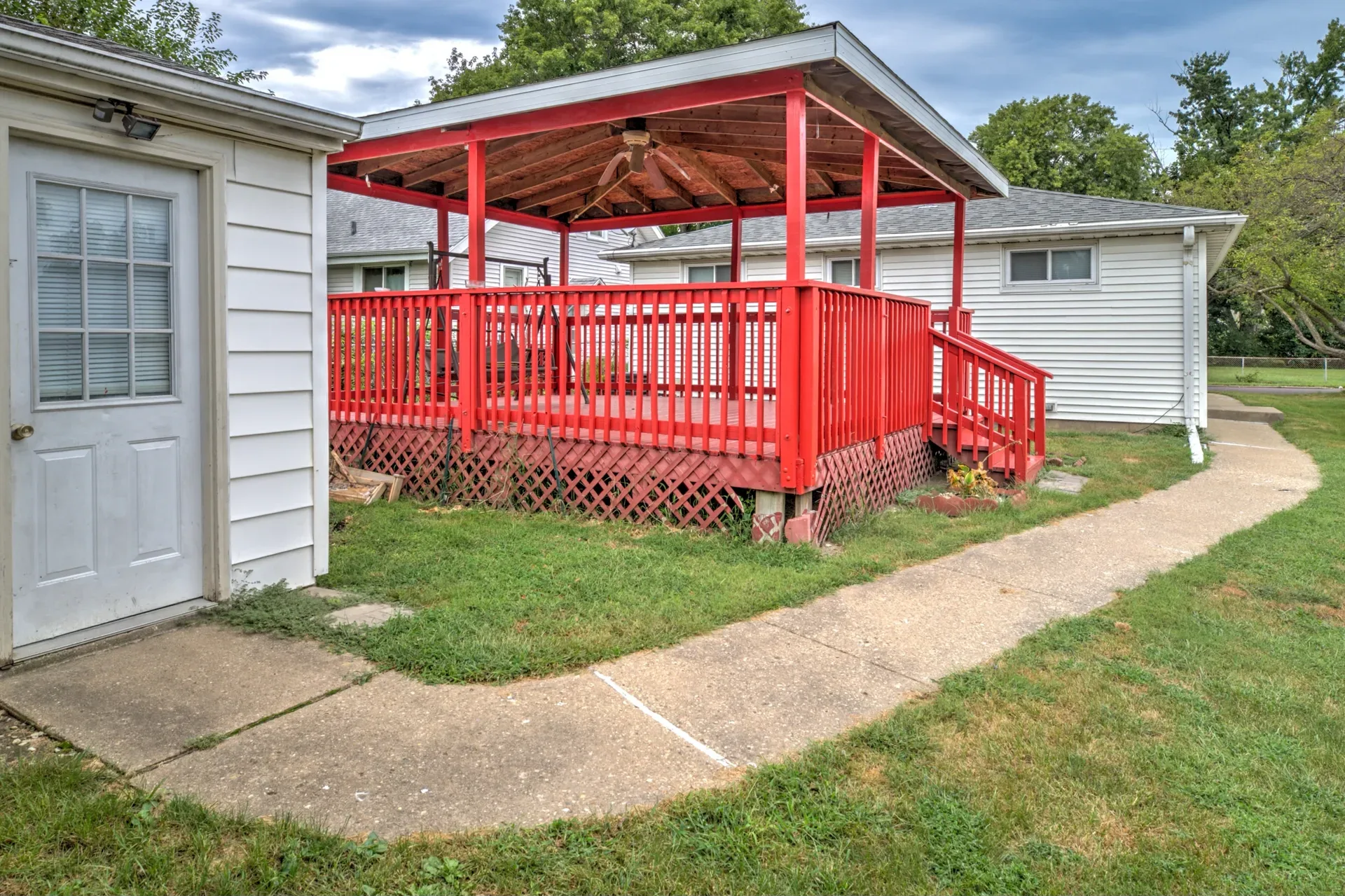 Bright red covered wooden deck with lattice skirting and a porch swing