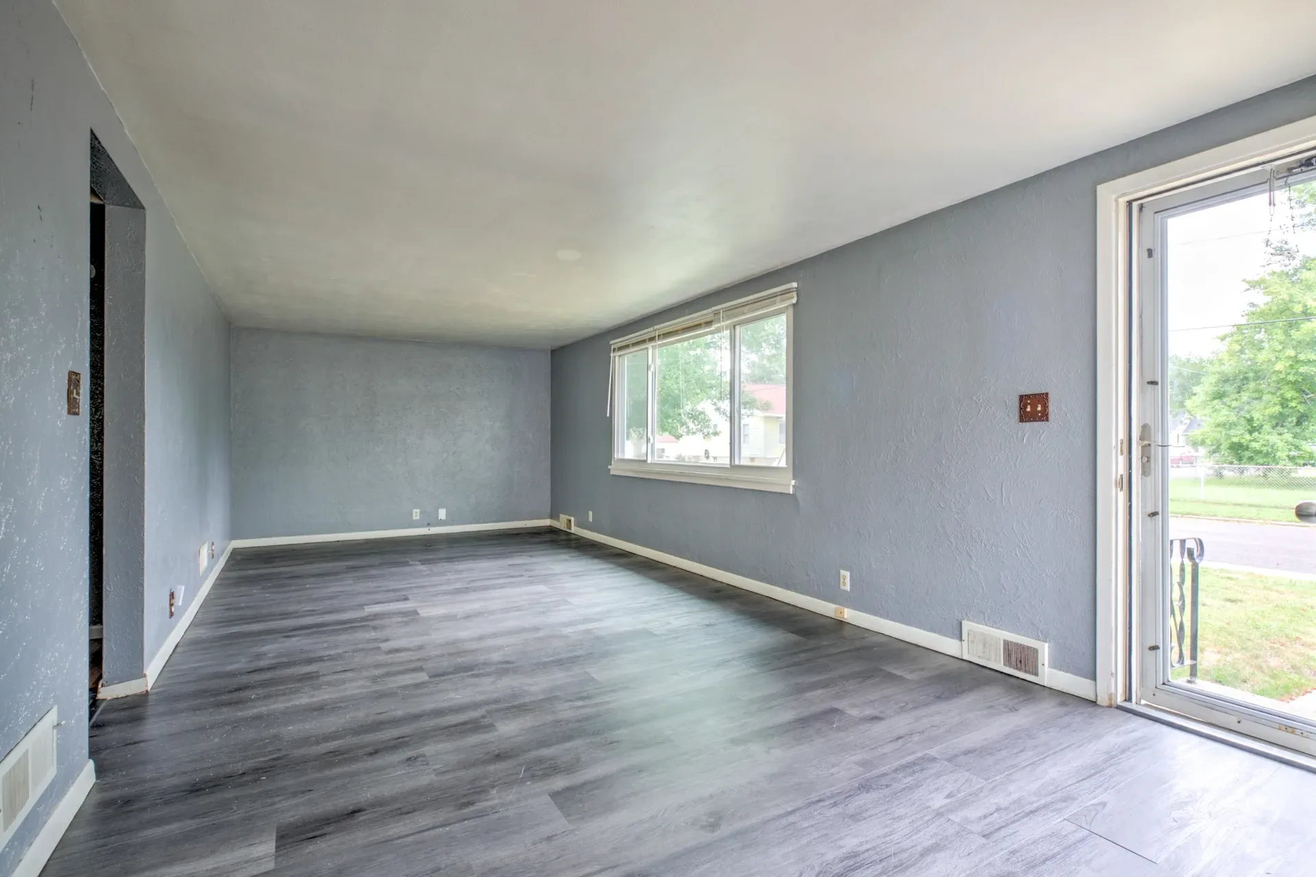 Living room viewed from the front door, vacant with wood-look plank flooring