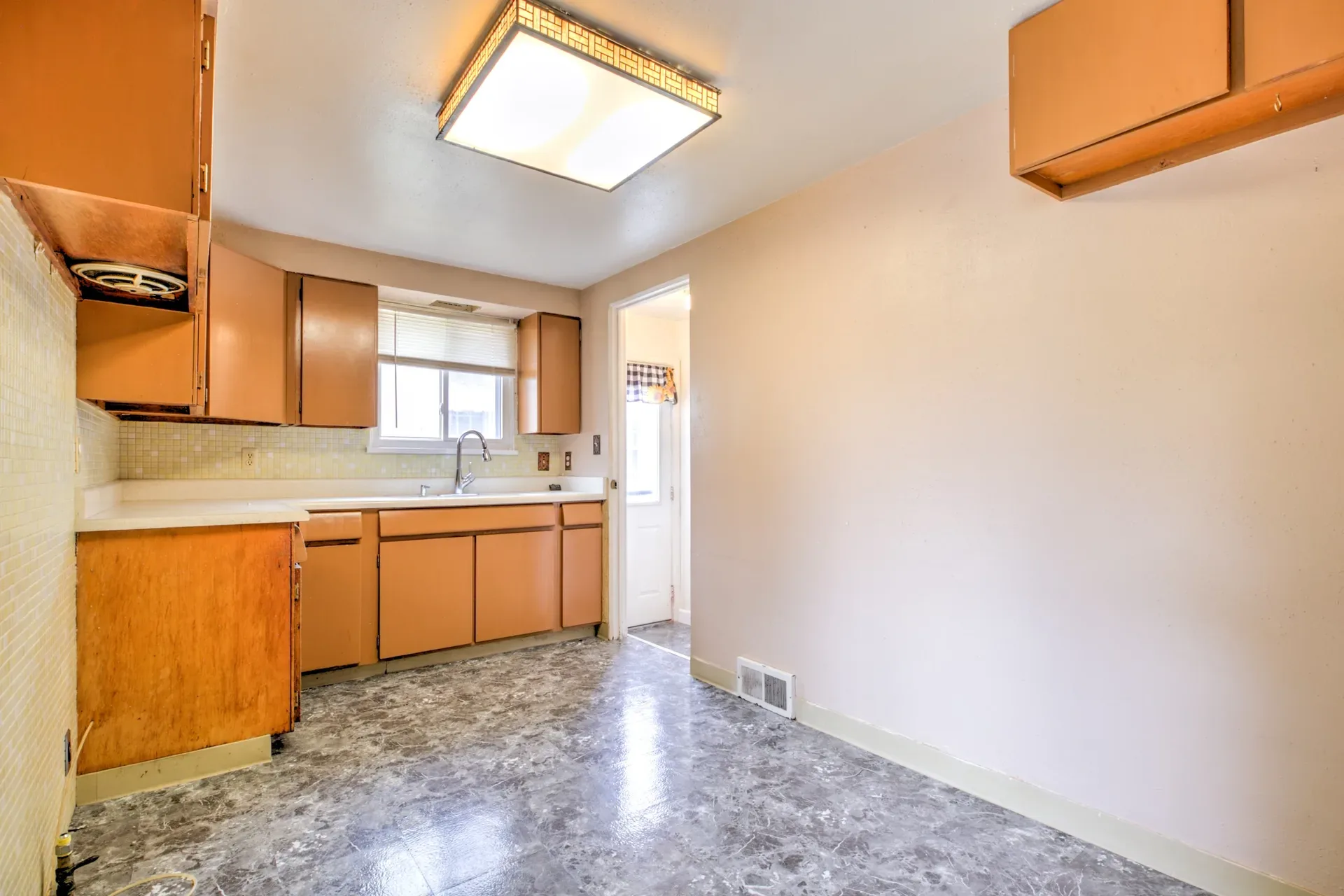 Kitchen with wood cabinets, white laminate countertops, and linoleum flooring