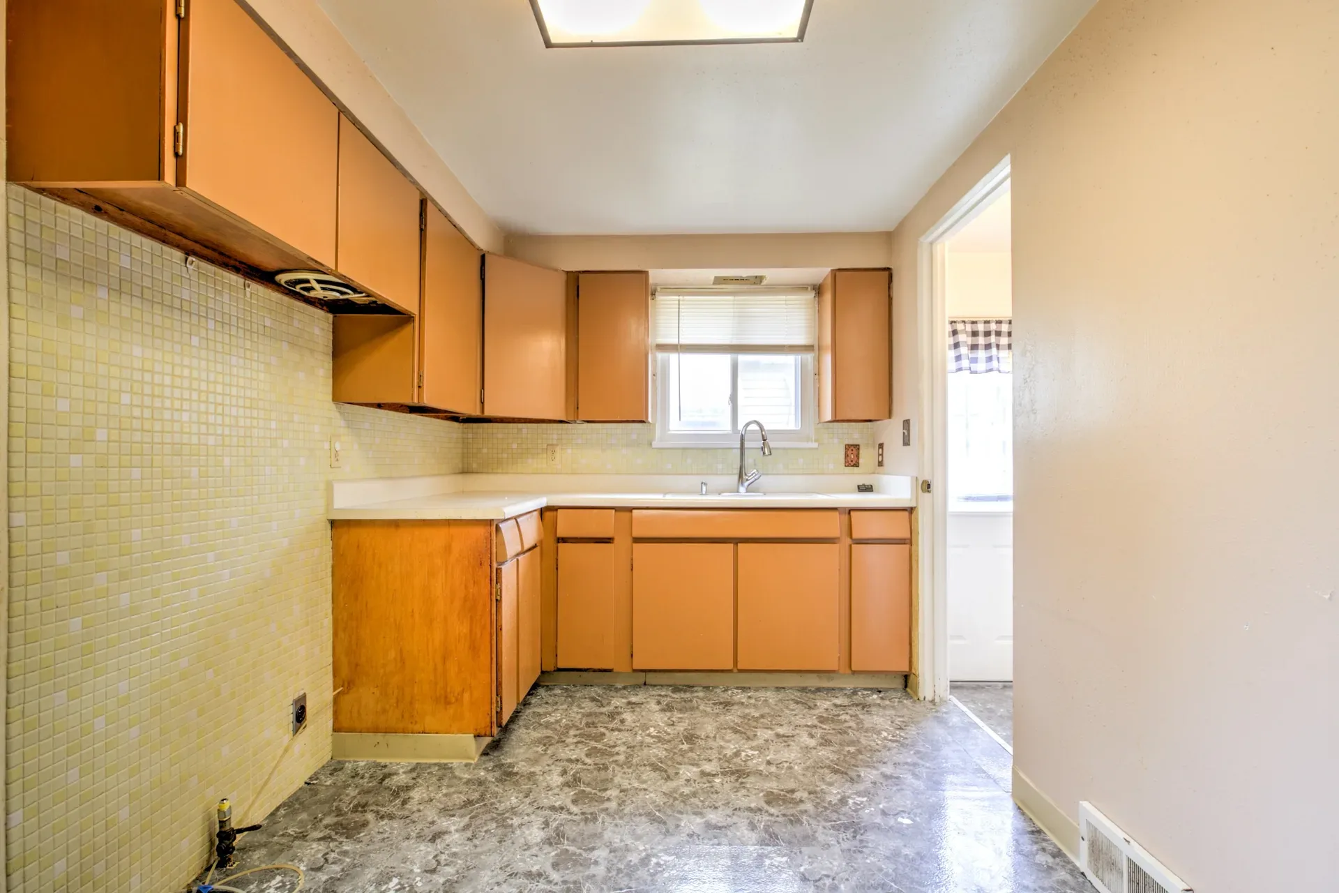 Kitchen with wood cabinets, light countertops, and mosaic tile backsplash at 902 E Maywood Ave