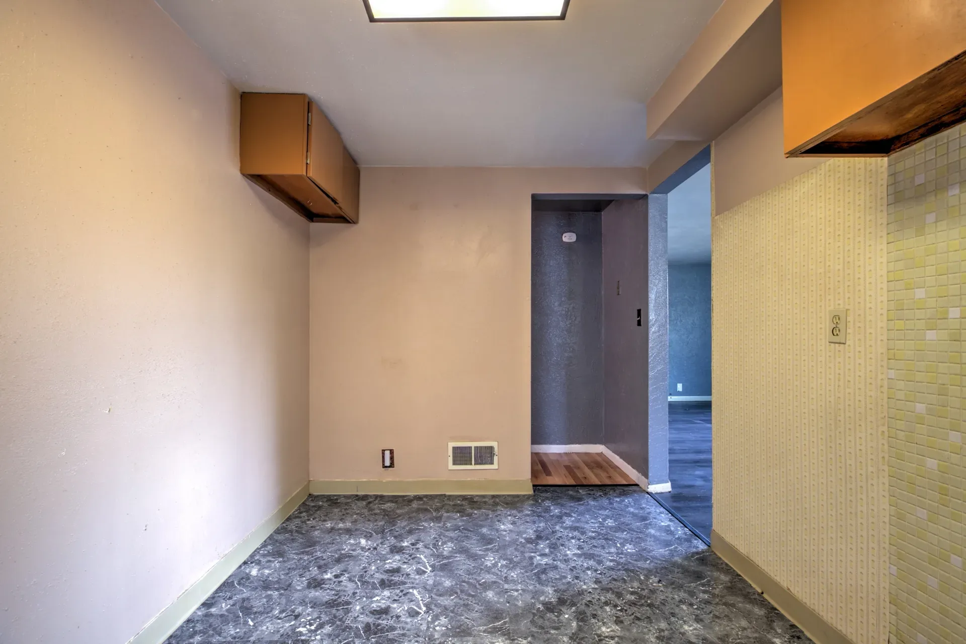 Kitchen area with wall-mounted cabinets, vinyl flooring, and textured backsplash