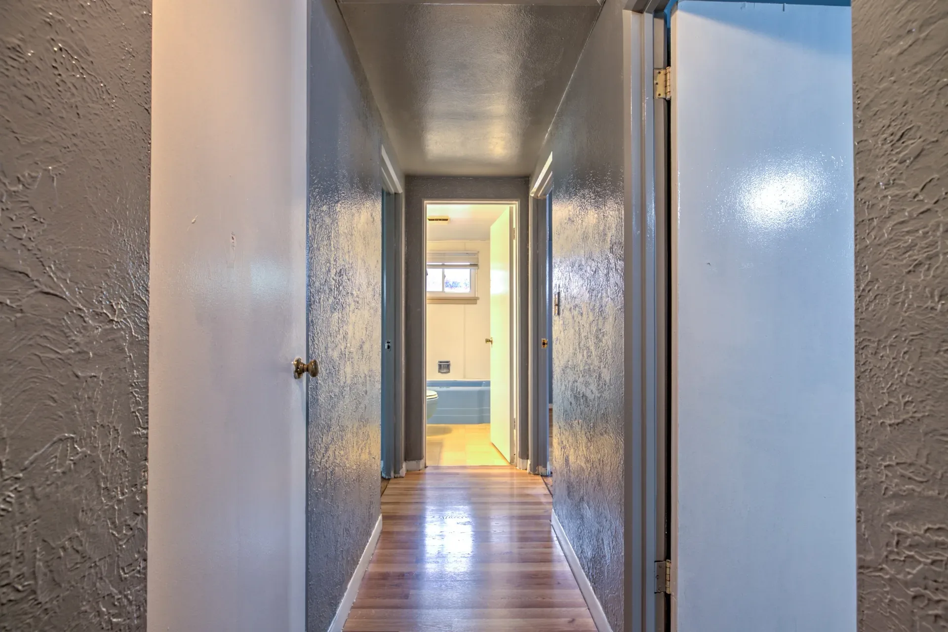 Interior hallway with textured grey walls, white trim, and wood-look flooring
