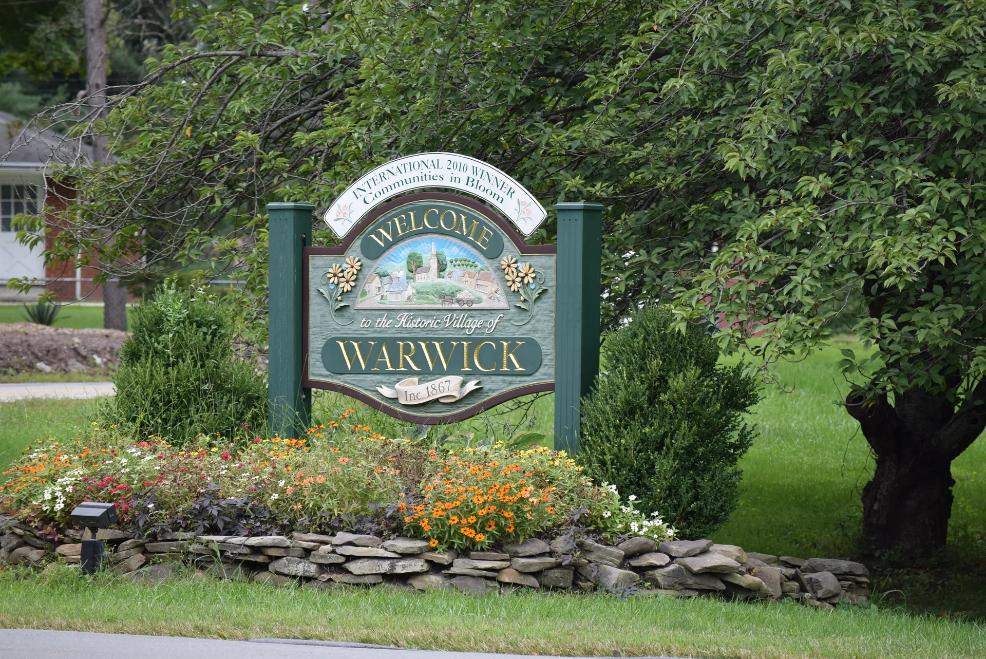 Welcome sign at the entrance to the Village of Warwick, surrounded by flowers