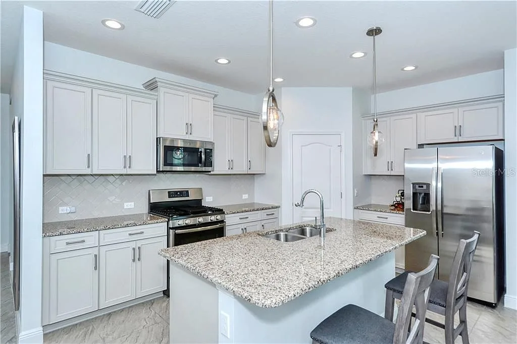 Modern grey kitchen with stainless appliances and pendant lights