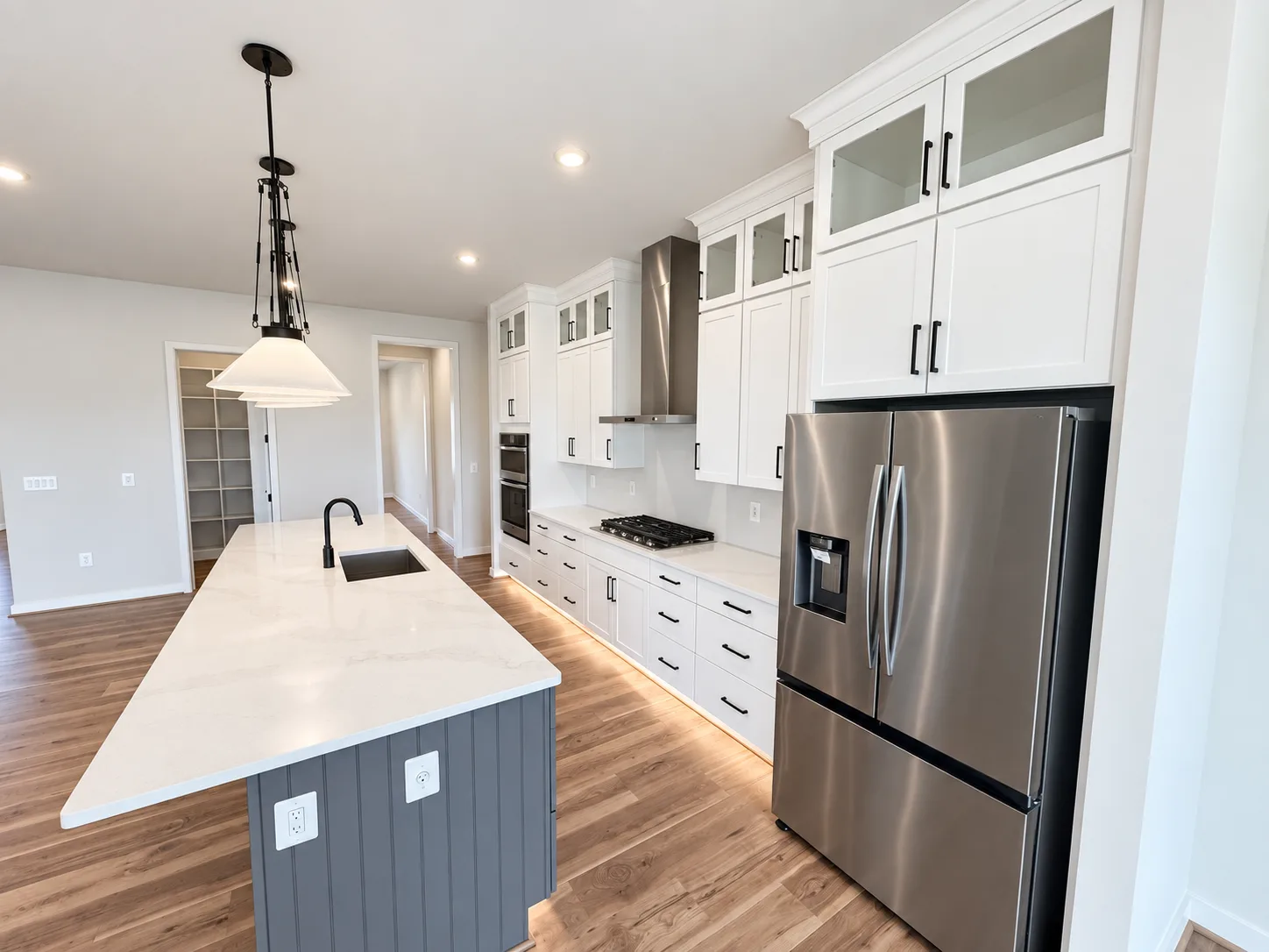Wide-angle view of the modern kitchen with quartz counters and a gray island base in the Torrey at Hampstead