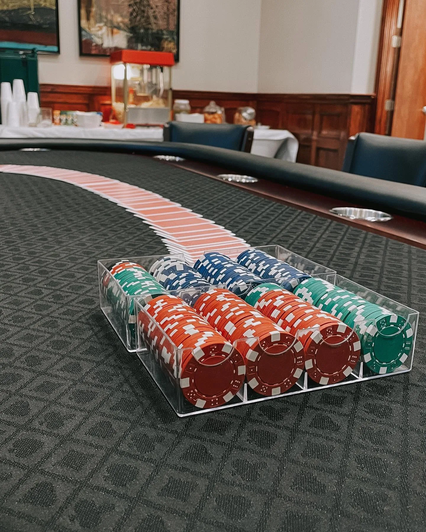 Poker table set for game night with a rack of chips, a spread of cards and a popcorn machine in the River Crossing clubhouse