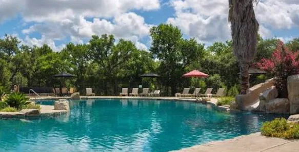 Rock rimmed backyard swimming pool with a built in stone slide at Patrick's River Crossing home