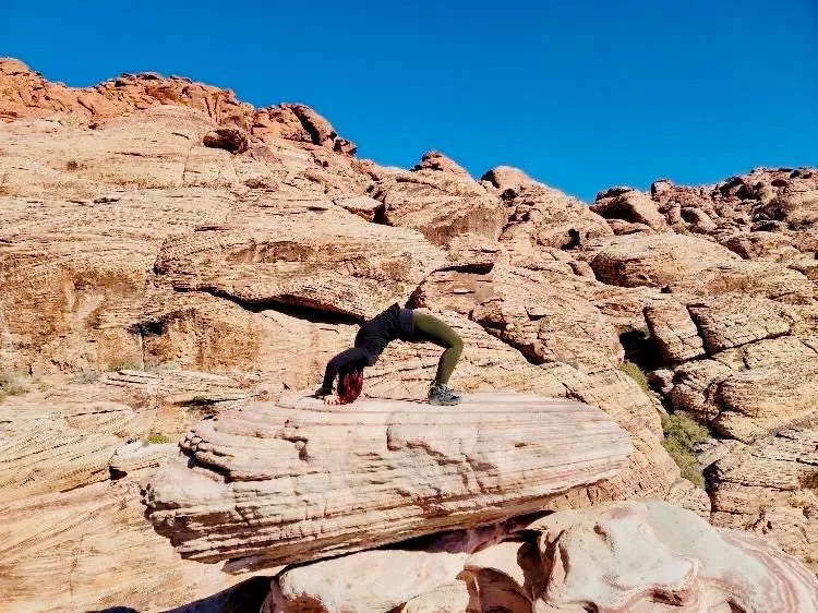 Samantha Medeiros practicing a yoga bridge pose on red rock formations at Red Rock Canyon