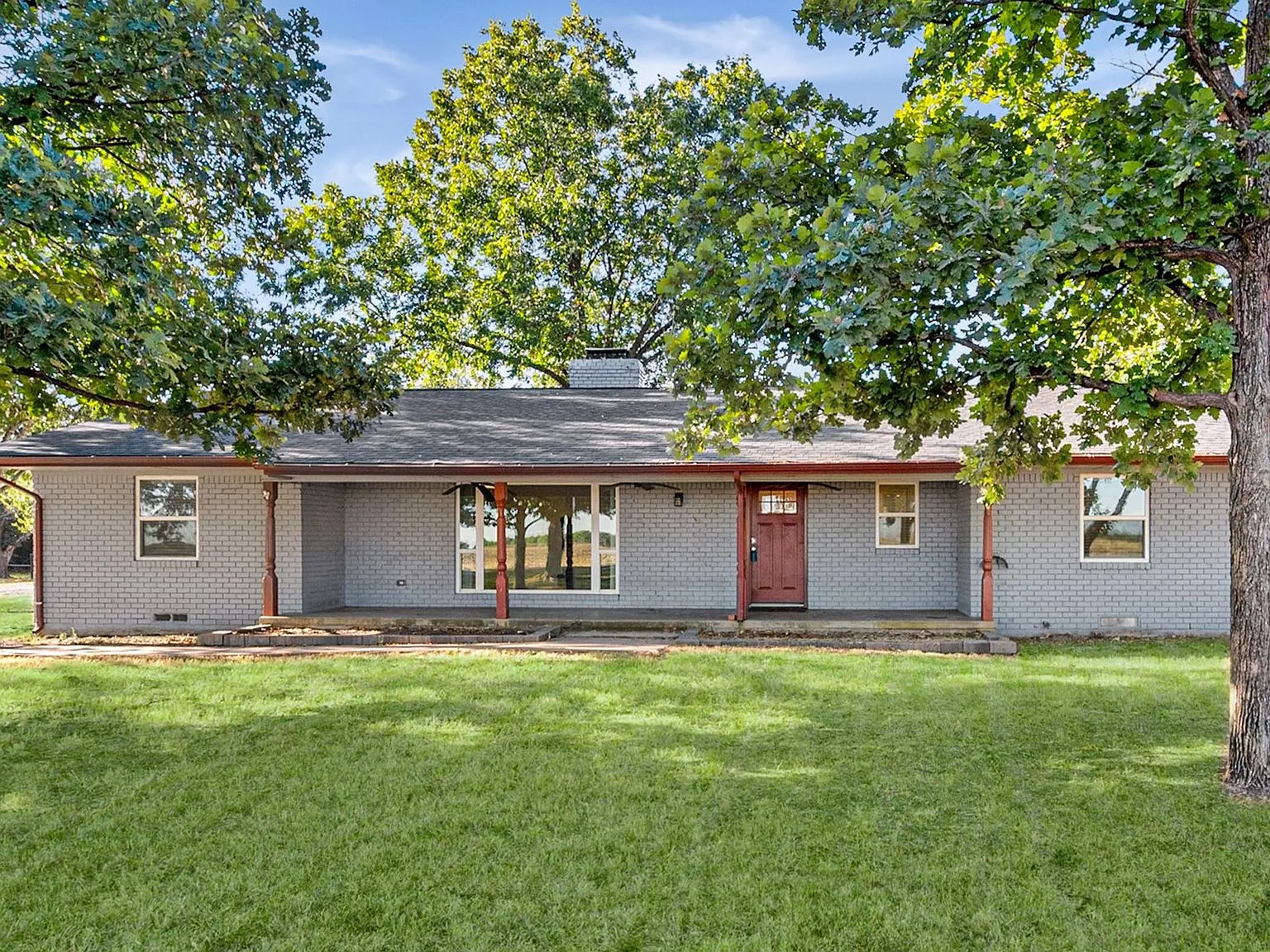 Front exterior of the renovated painted-brick ranch home at 917 Goodwyn Rd, shaded by mature oaks