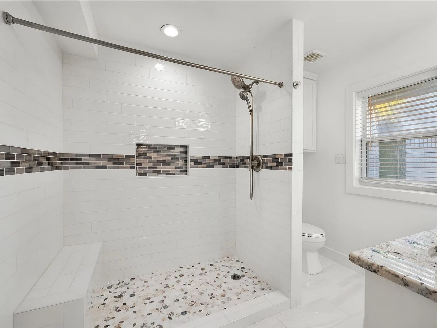 Renovated bathroom with tiled walk-in shower, mosaic niche and brushed-nickel fixtures