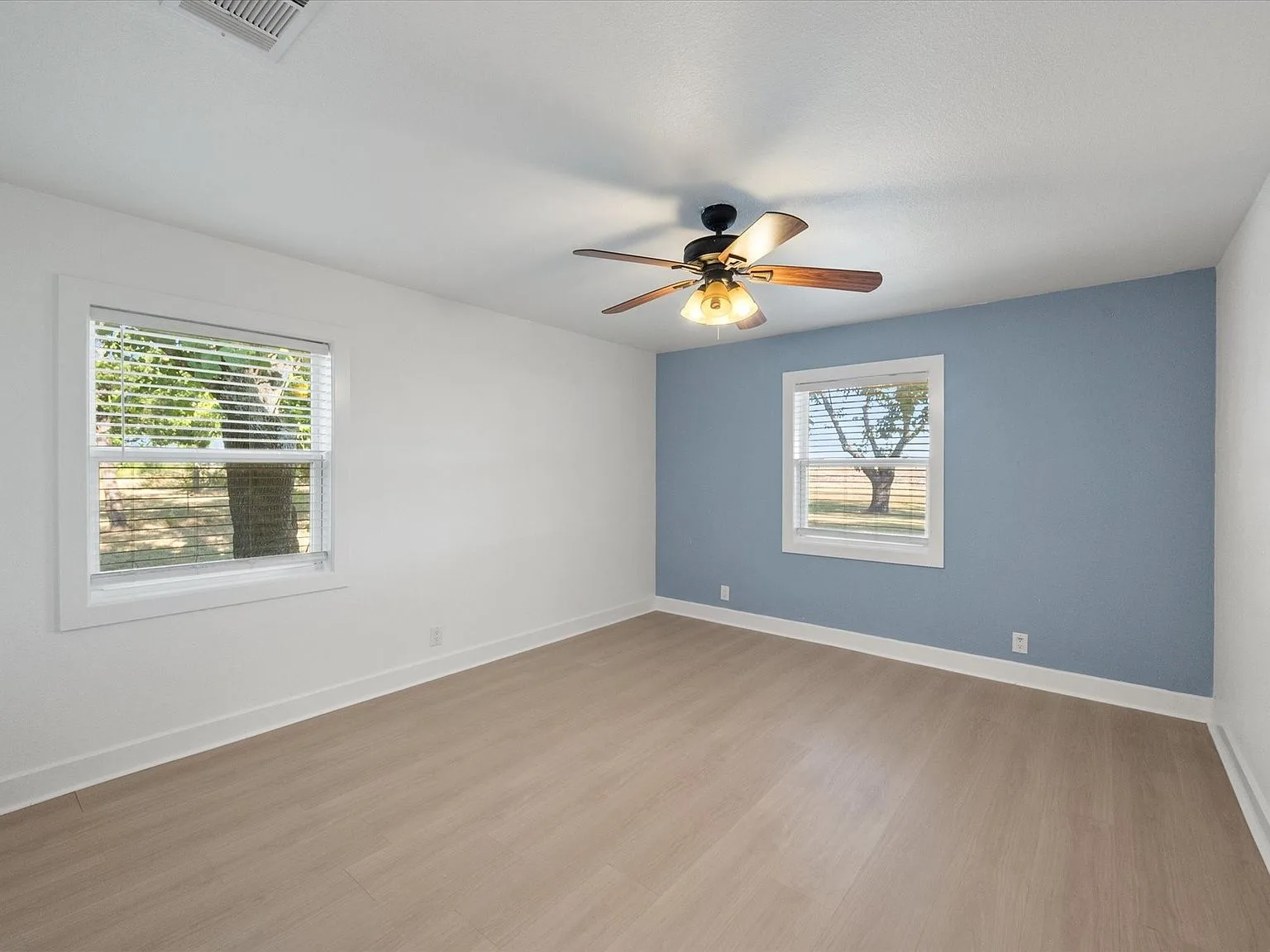 Renovated bedroom with blue accent wall and bright windows