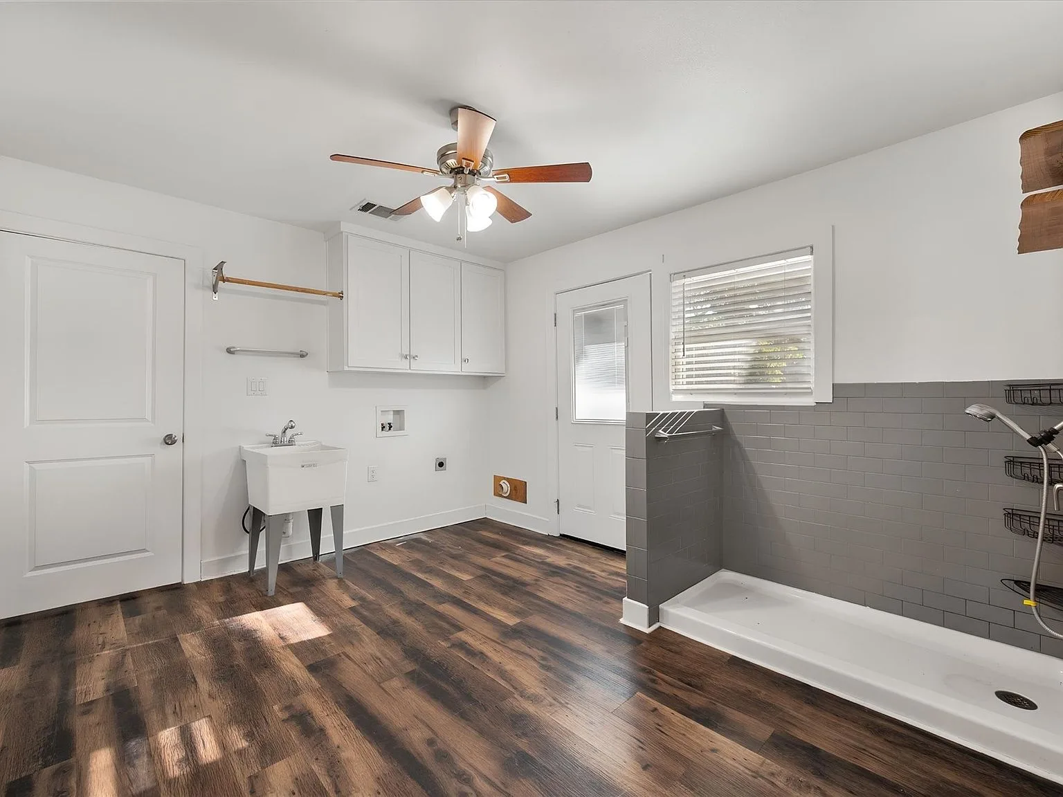Renovated utility and mudroom with a tiled shower area, utility sink and plank flooring
