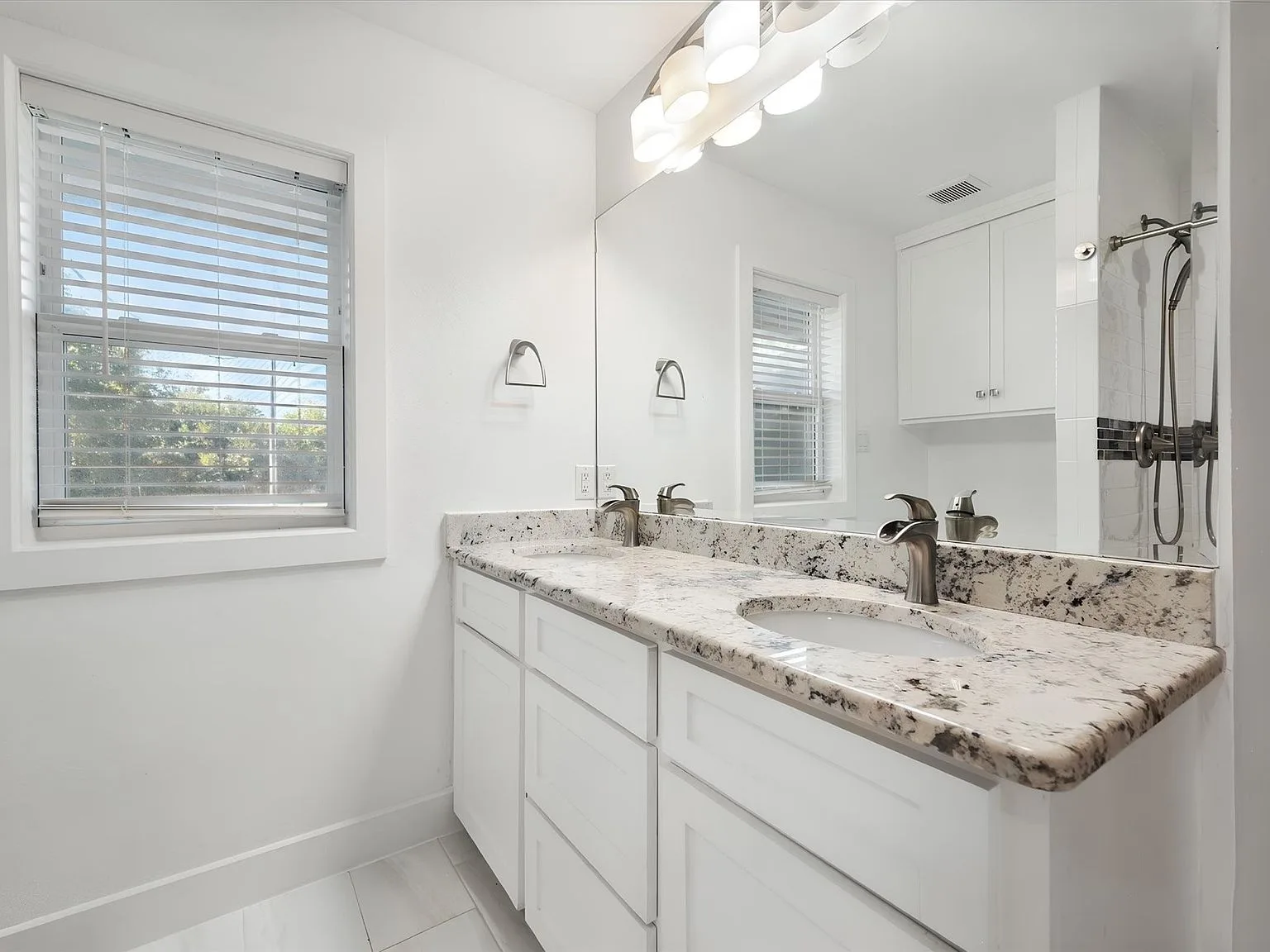 Updated bathroom vanity with dual sinks, granite counters and brushed-nickel fixtures