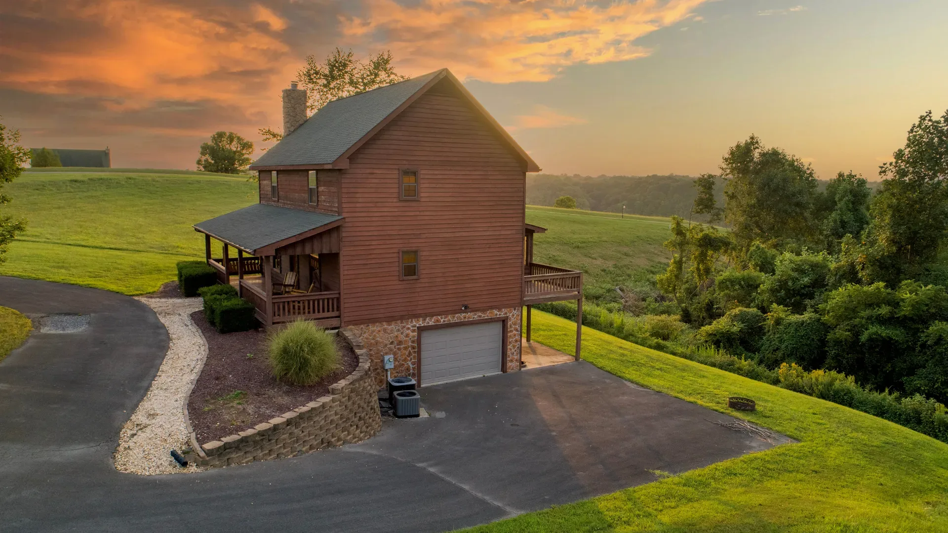 A rustic log cabin on a large grassy lot in rural Kentucky at sunset, seen from above