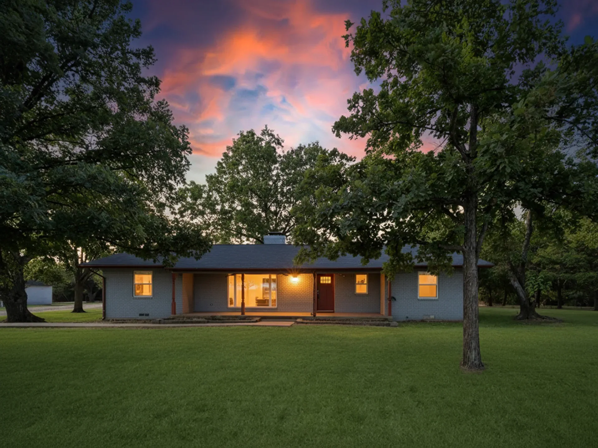 Front exterior of the ranch home at dusk with warm light glowing from the windows