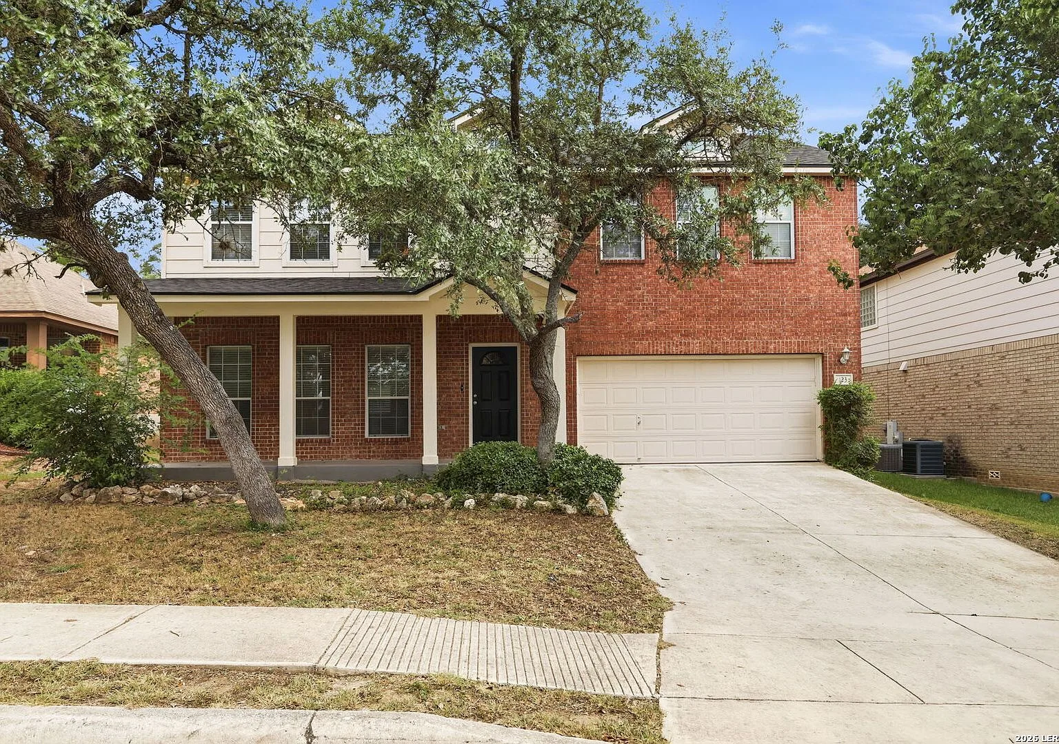 Front view of the two-story red brick home at 123 Impala Cir, San Antonio, TX