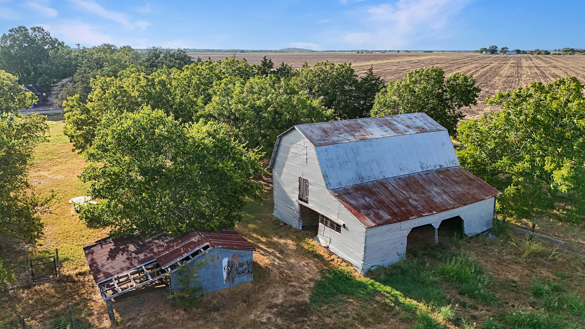 Drone aerial of the rustic barn and outbuildings set among open fields and mature trees