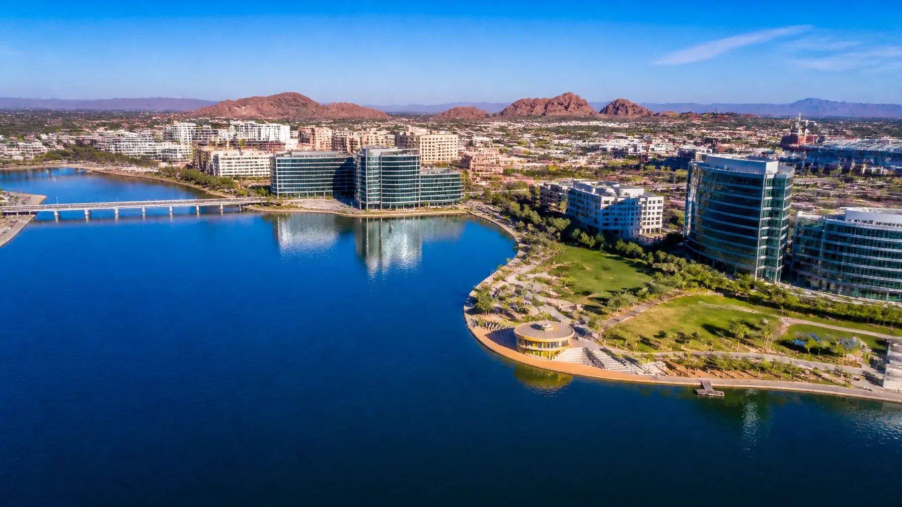 An aerial view of a lakefront office park with a bridge and walking paths