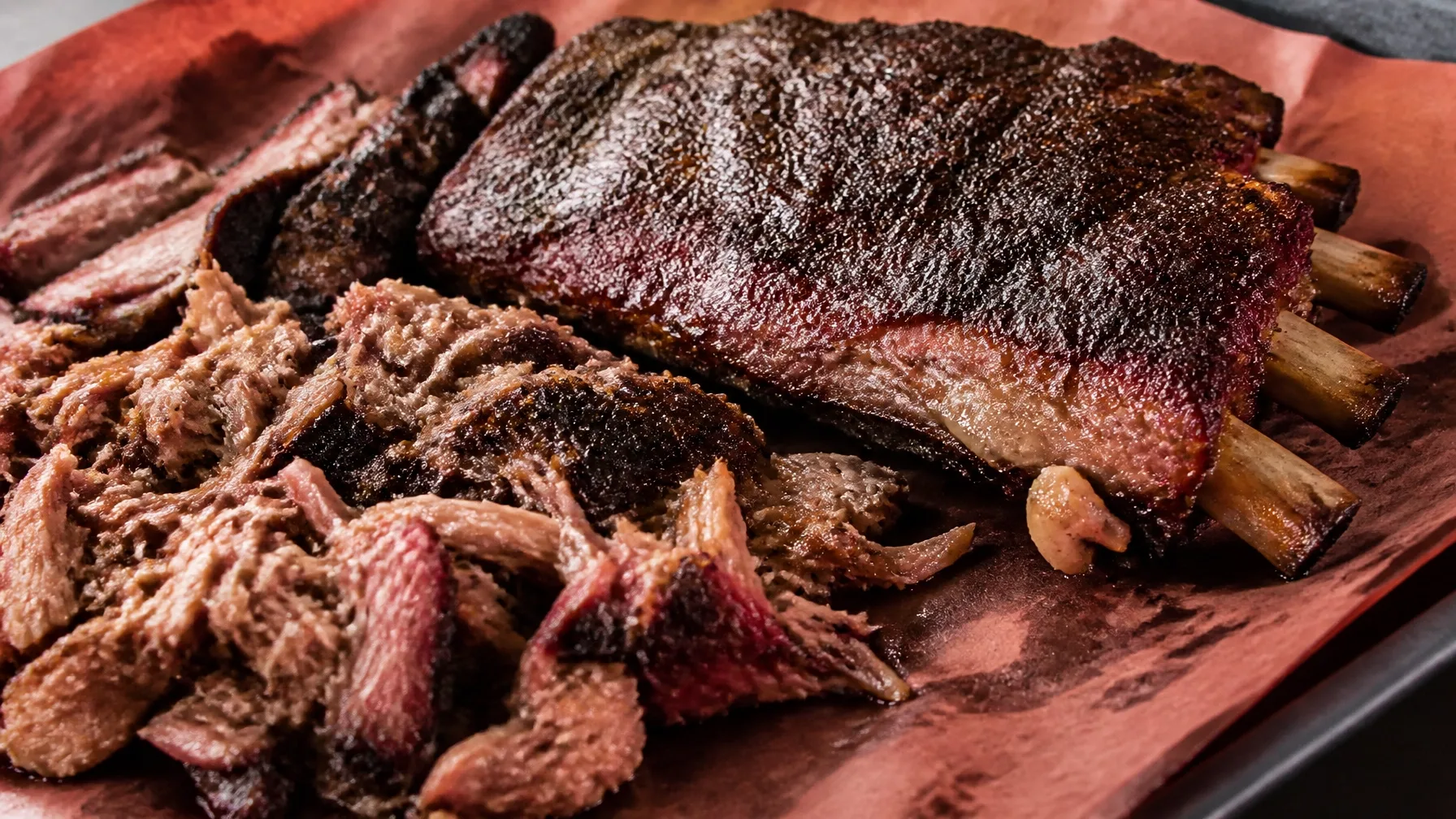 Smoked barbecue ribs on butcher paper with a dark, charred bark