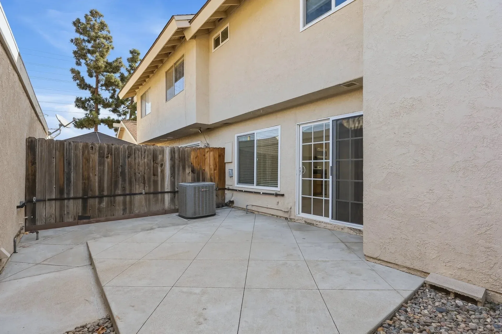 Private patio at 8 Silverwood as photographed, unfurnished, with a paved concrete surface, gravel border, and wood privacy fence