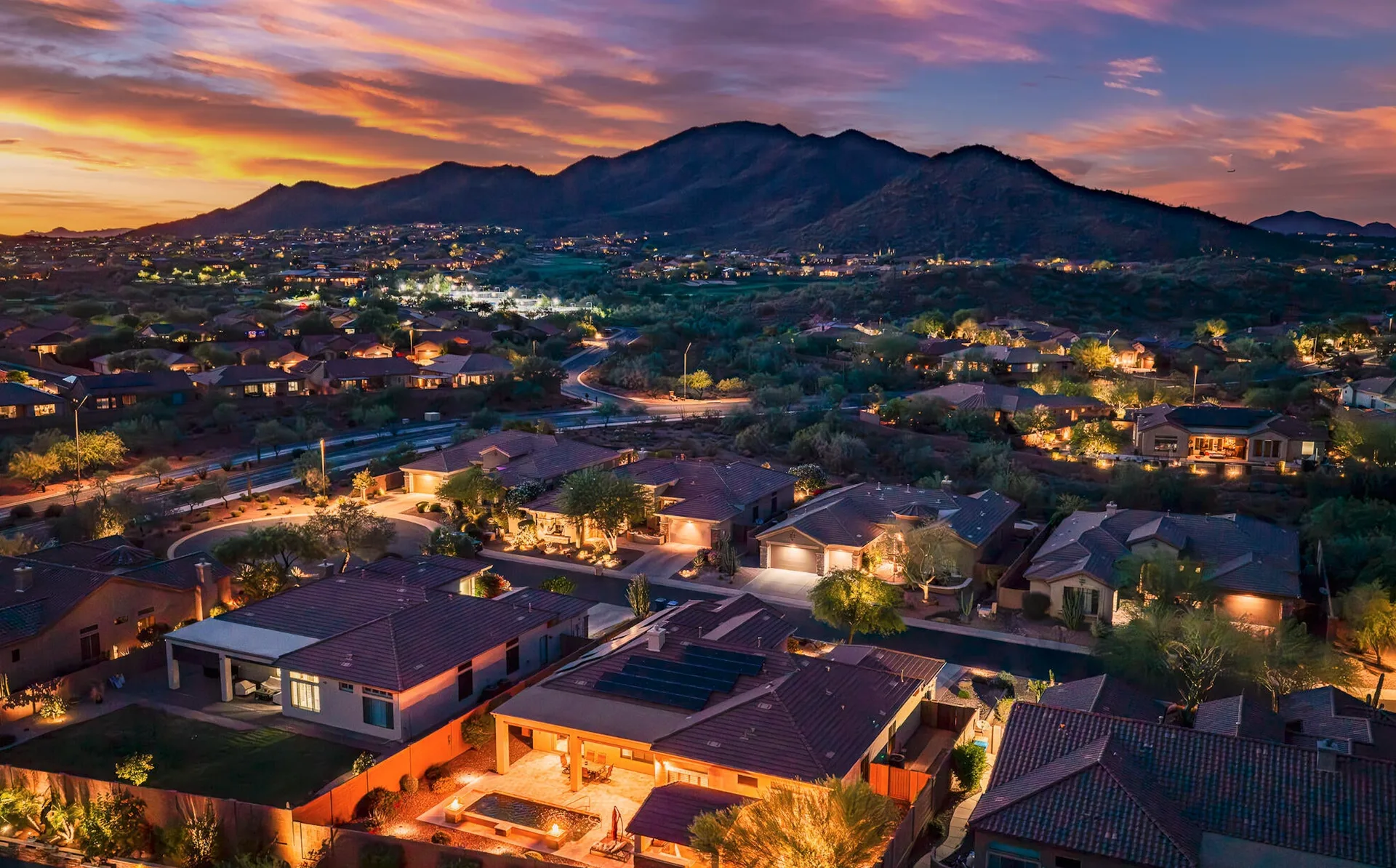 An aerial view of a residential neighborhood at twilight with mountains in the distance