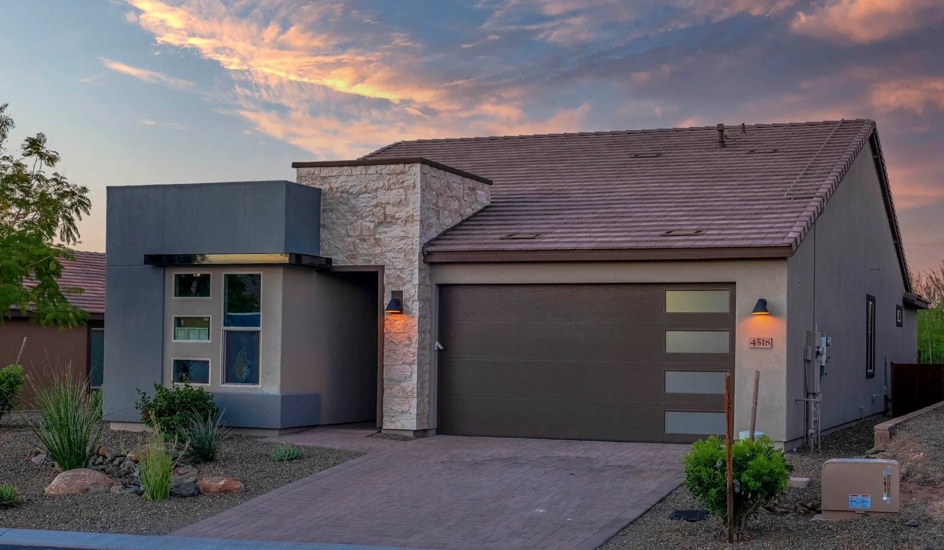 A single-story desert-style home with stucco and stone accents at sunset