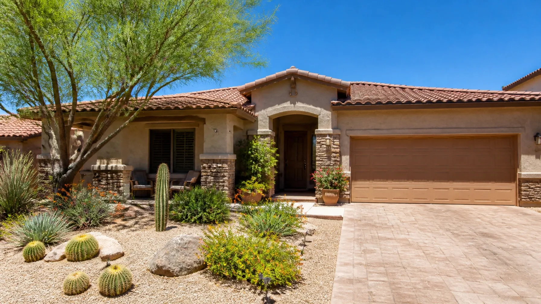A desert-style home with stucco and stone accents and a furnished front patio