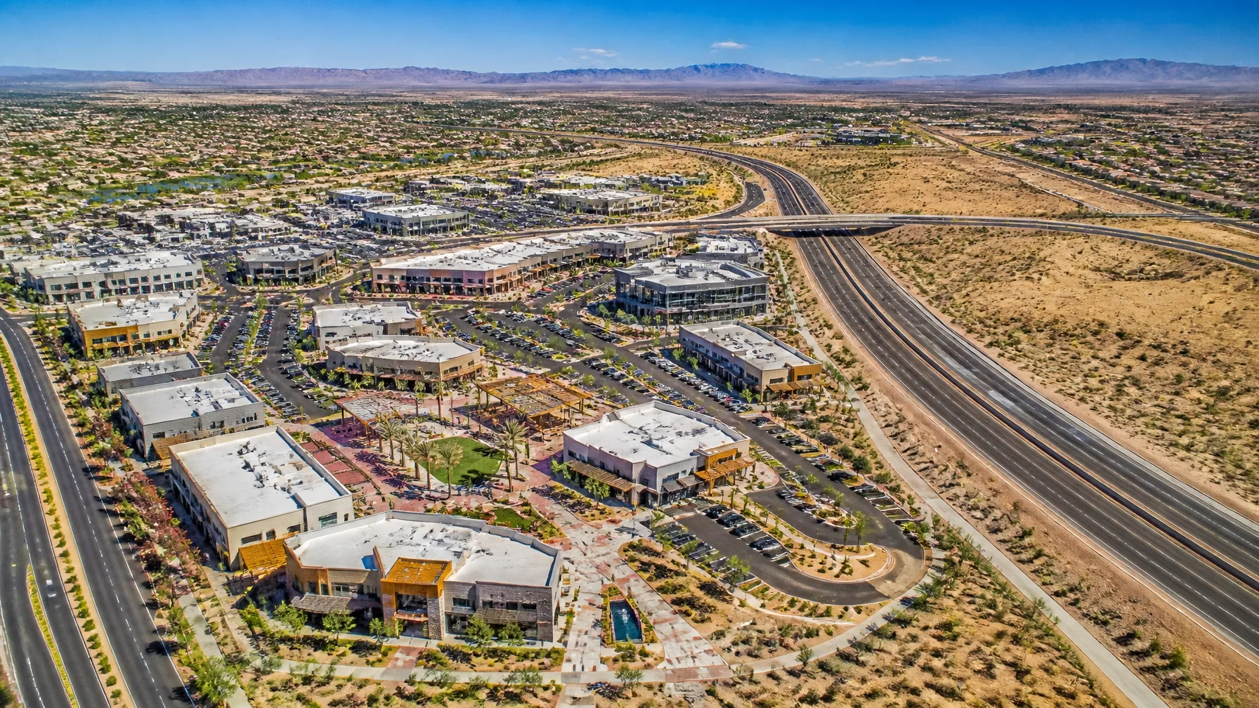 An aerial view of a suburban commercial center beside a major highway interchange
