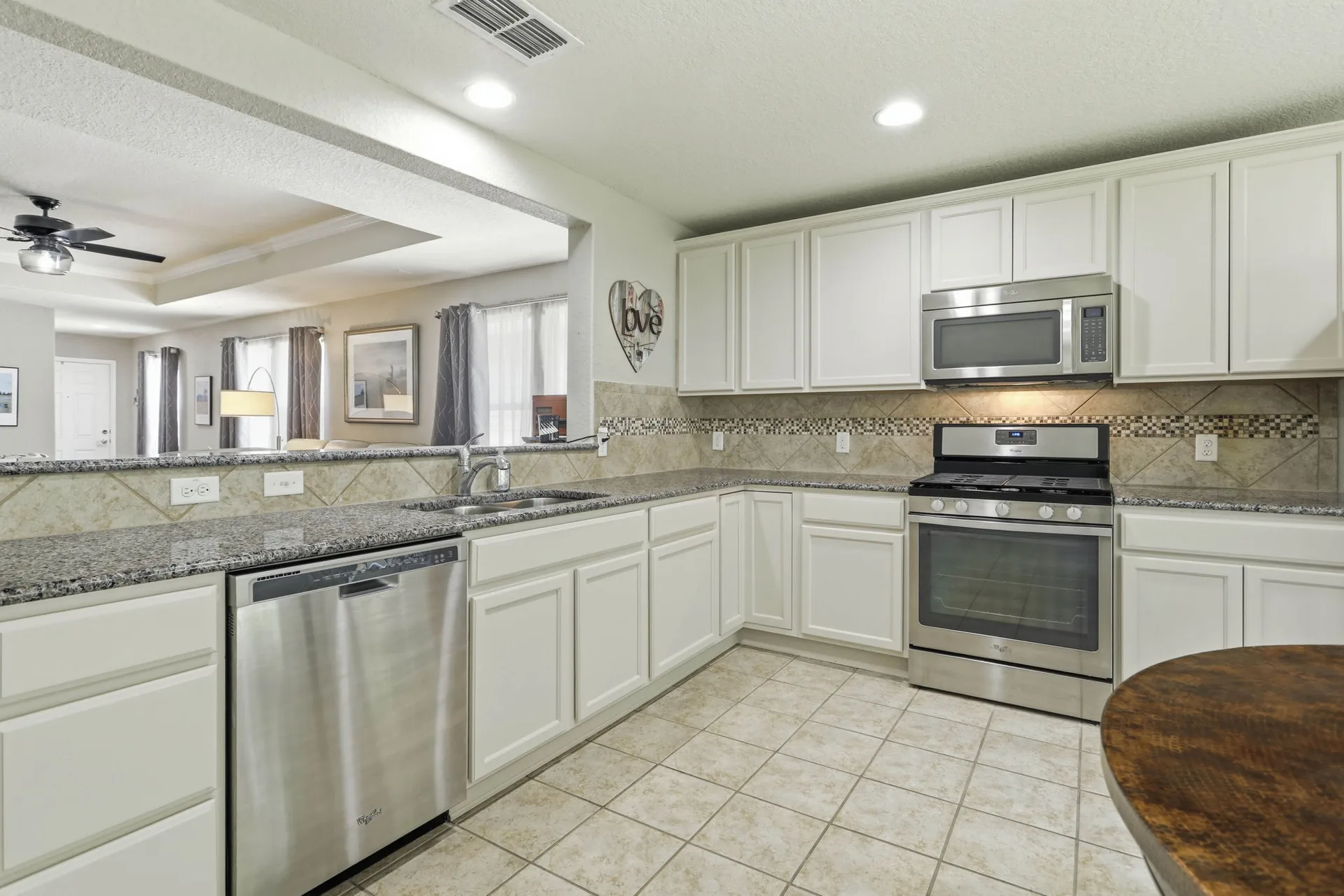 Open concept kitchen with granite countertops, cream cabinetry, and stainless steel appliances