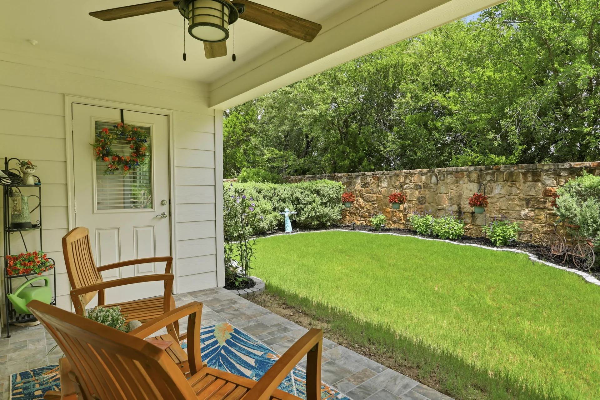 Covered back patio with ceramic tile flooring overlooking the landscaped backyard