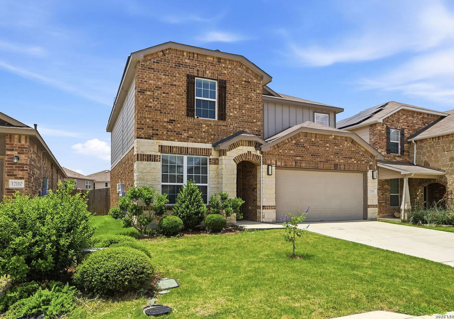 Front facade with brick and stone veneer, wood shutter accents, and a two-car garage.