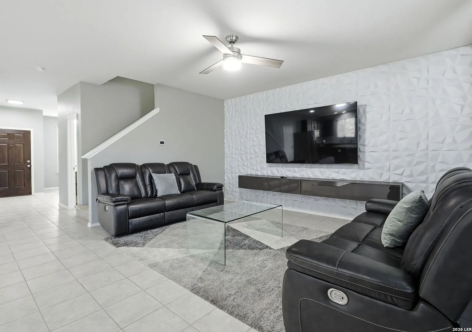 Living room with a 3D textured accent wall and ceramic tile flooring.