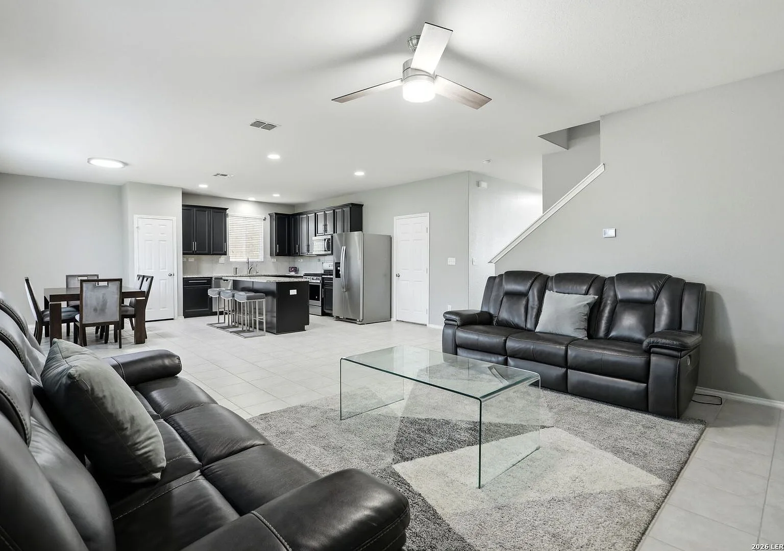 Open-concept living and kitchen space with dark cabinetry and granite counters.