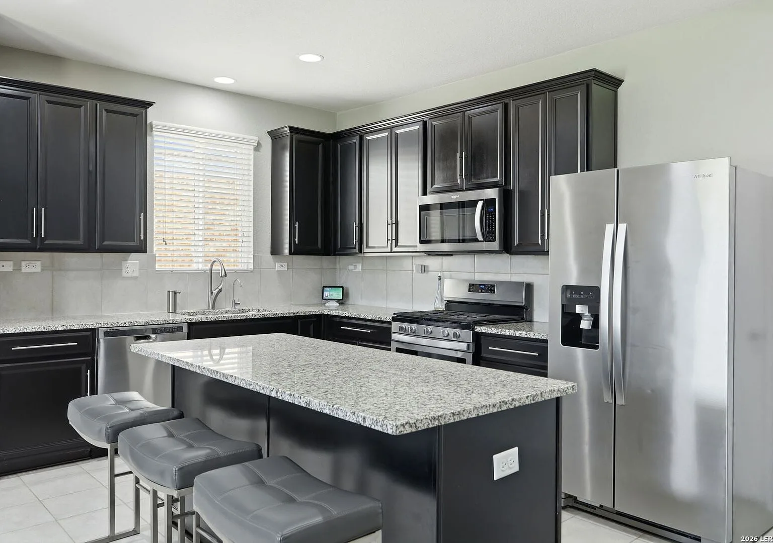 Modern kitchen island with dark cabinetry, granite counters, and stainless steel appliances.
