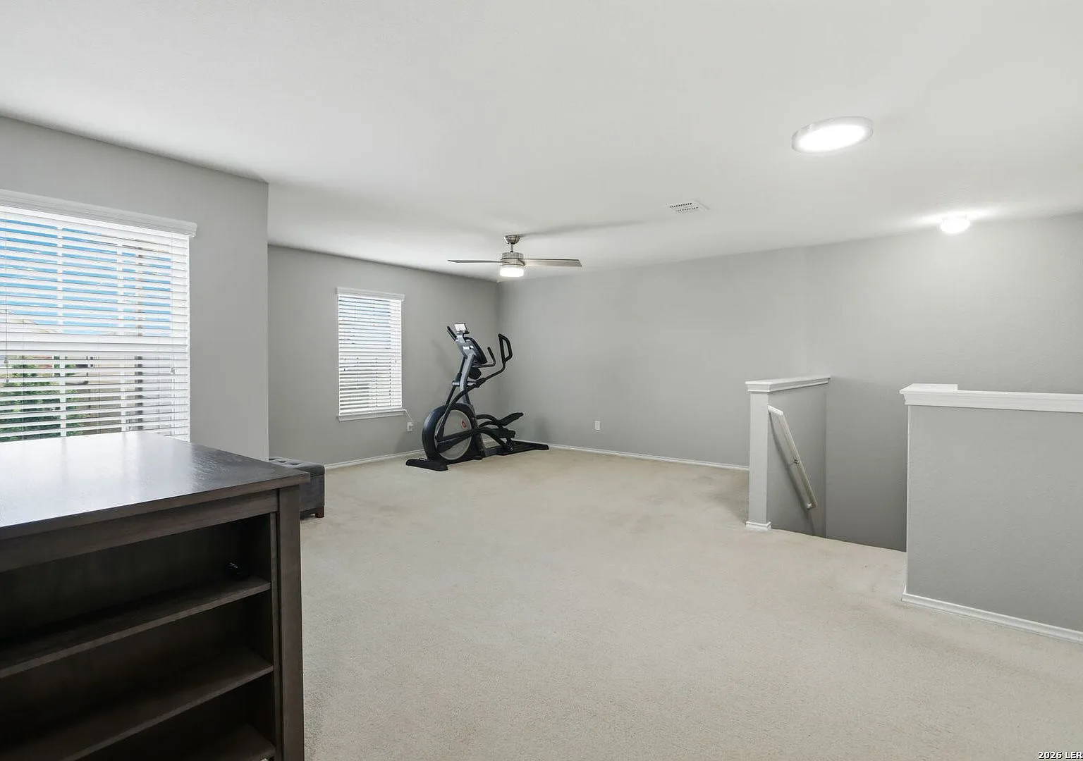 Upstairs game room with neutral grey walls and beige carpet.